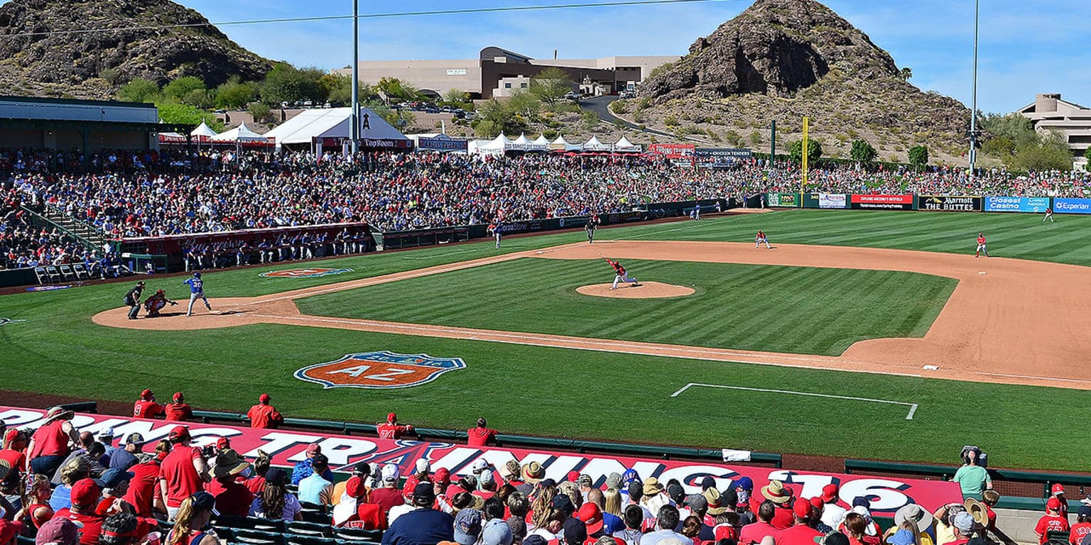 Spring training baseball game in Mesa, Arizona with a packed stadium crowd and the iconic desert buttes rising behind the outfield
